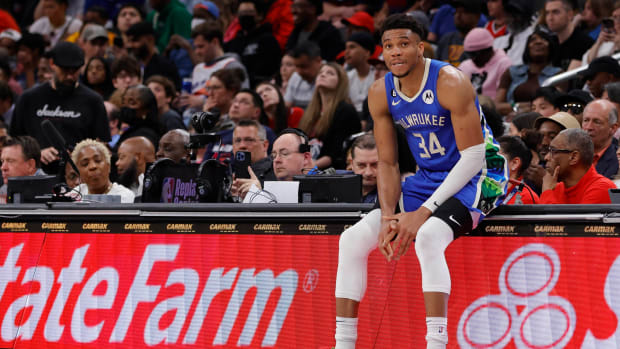 Milwaukee Bucks forward Giannis Antetokounmpo sits on the scorers table during a timeout.
